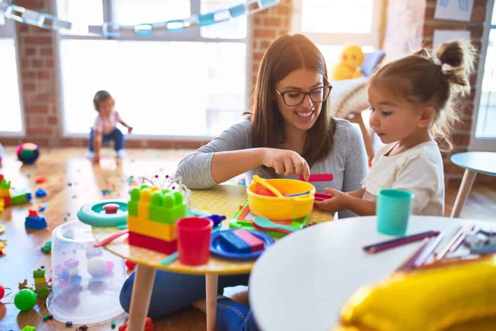 A woman plays pretend meal time with a girl in a room full of toys