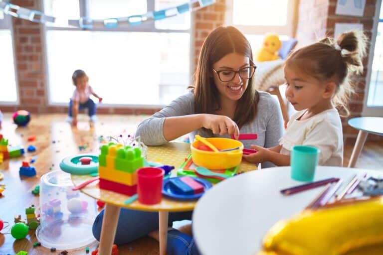 A woman plays pretend meal time with a girl in a room full of toys