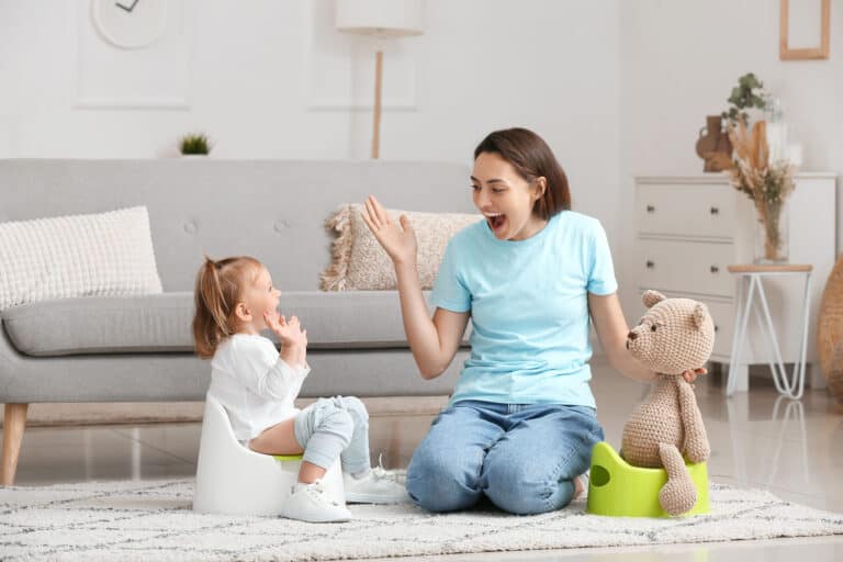 Woman teaching a girl child to use the potty in her living room