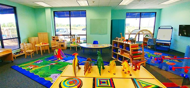 Bright indoor playroom with toys, mats, and activity stations for children.