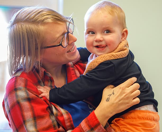 Woman Holding Smiling Baby Indoors Natural Light