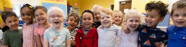 Smiling, happy children standing in a line and hugging each other.