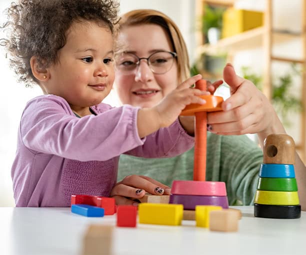 Childcare Teacher Toddler Learning With Blocks