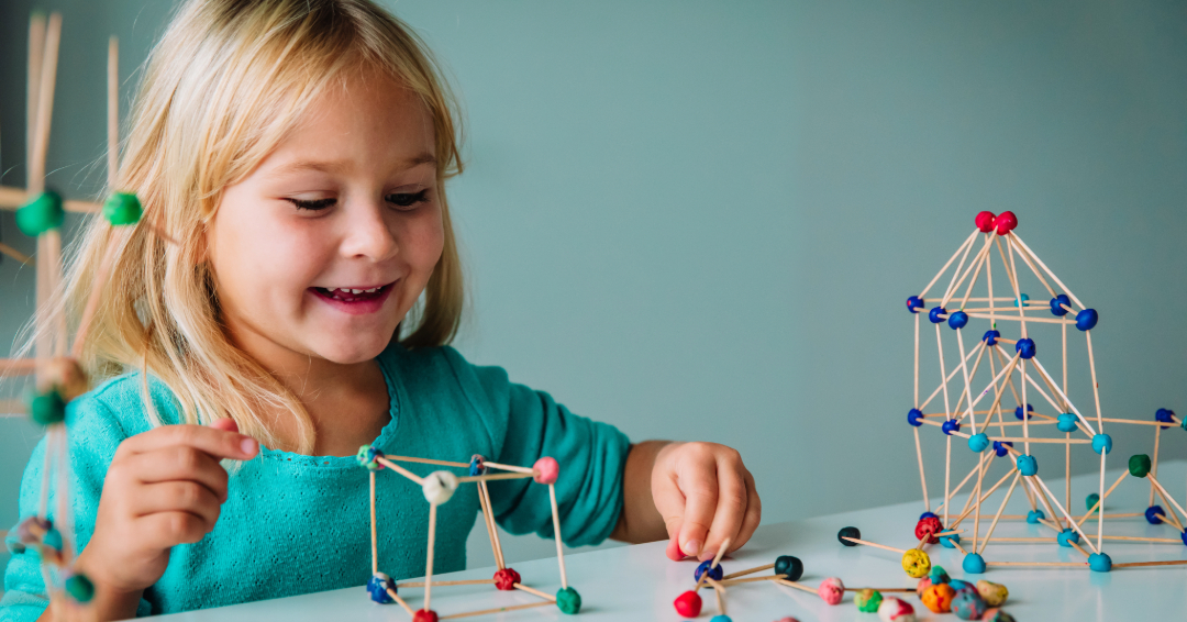 Preschooler creating buildings from toothpicks and clay.