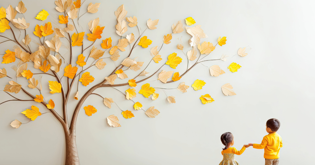 Preschool boy and girl hold hands standing before a fall craft tree.